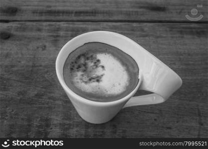 Cup of cappuccino coffee on wooden table, black and white tone