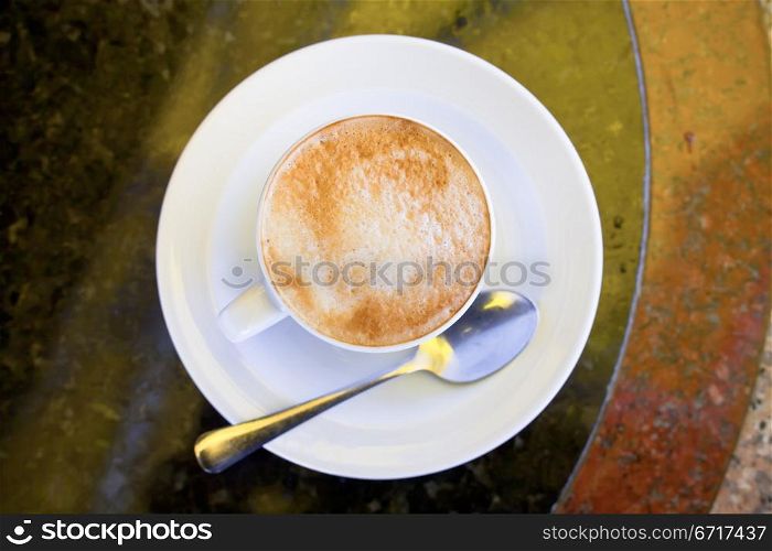 cup of cappuccino on stone table in outdoor cafe