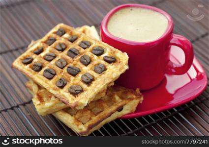 cup of cappuccino wafers and coffee beans on a bamboo mat