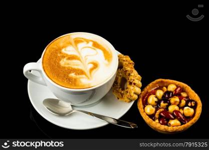 cup of cappucino and cakes on black background