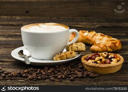 cup of cappucino and cakes on dark background