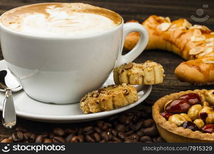 cup of cappucino and cakes on dark background