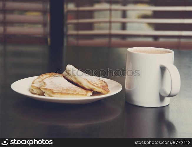 cup of cocoa and Fresh pancakes with sugar.