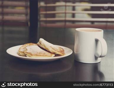 cup of cocoa and Fresh pancakes with sugar.