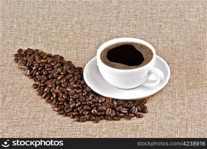 Cup of coffe and coffe beans on burlap background