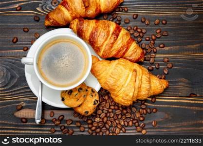 cup of coffe and croissant on dark wooden background. cup of coffe and croissant on wooden background