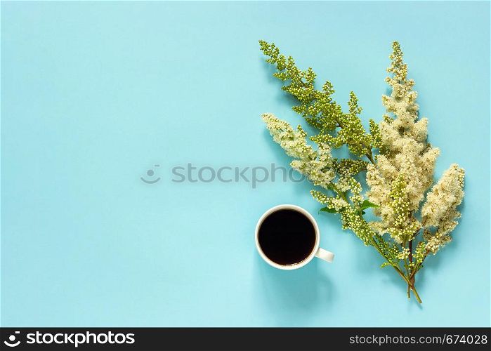 Cup of coffee and blooming twig white flowers on blue paper background Flat lay Top view Concept Good morning or Hello spring Copy space Template for postcard, text or your design.. Cup of coffee and blooming twig white flowers on blue paper background Flat lay Top view Concept Good morning or Hello spring Copy space Template for postcard, text or your design