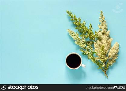 Cup of coffee and blooming twig white flowers on blue paper background Flat lay Top view Concept Good morning or Hello spring Copy space Template for postcard, text or your design.. Cup of coffee and blooming twig white flowers on blue paper background Flat lay Top view Concept Good morning or Hello spring Copy space Template for postcard, text or your design