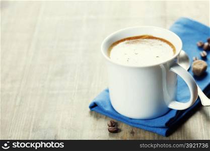 Cup of coffee and blue napkin on vintage wooden background