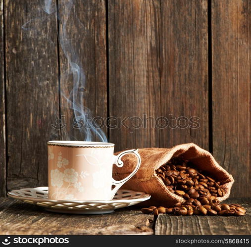 Cup of coffee and coffee beans in sack on wooden table