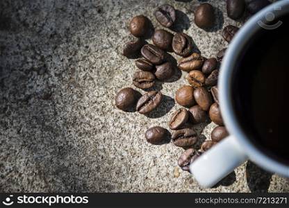 Cup of coffee and coffee beans on a stone background.. Cup of coffee and coffee beans on a stone background
