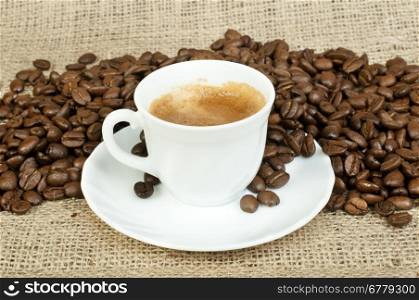 Cup of coffee and coffee beans on burlap