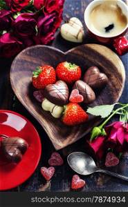 Cup of coffee and heart shape plate with strawberries and chocolate on wooden table - Valentine&rsquo;s day and love concept