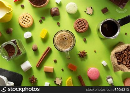 cup of coffee and ingredients at green paper background