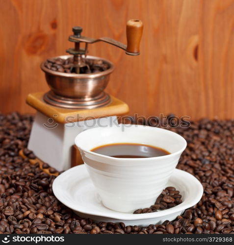 cup of coffee and roasted coffee beans with retro manual grinder