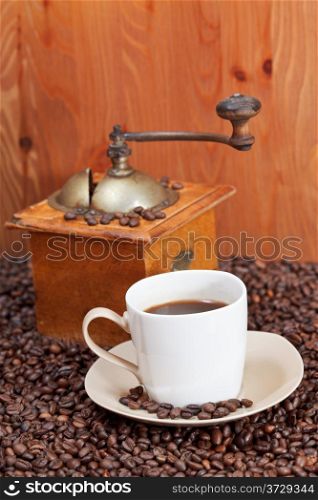 cup of coffee and roasted coffee beans with retro manual grinder near wooden wall