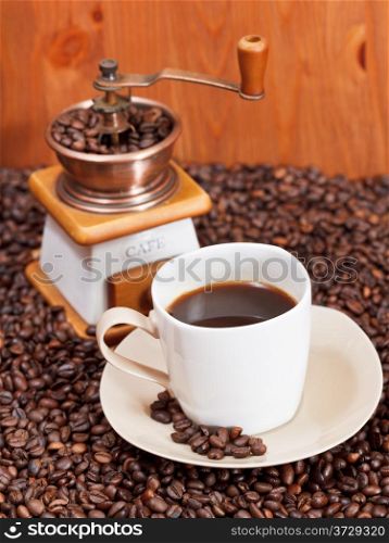 cup of coffee and roasted coffee beans with retro manual mill