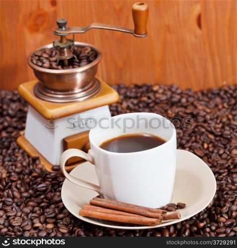 cup of coffee and roasted coffee beans with retro manual mill, cinnamon