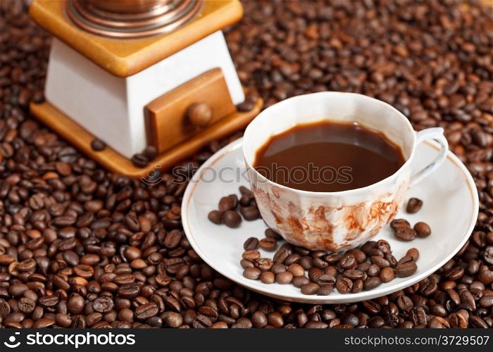 cup of coffee and roasted coffee beans with retro manual mill close up