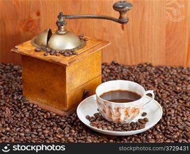 cup of coffee and roasted coffee beans with retro wood manual mill