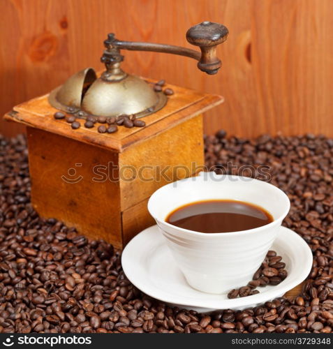 cup of coffee and roasted coffee beans with retro wooden manual mill