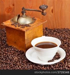 cup of coffee and roasted coffee beans with retro wooden manual mill