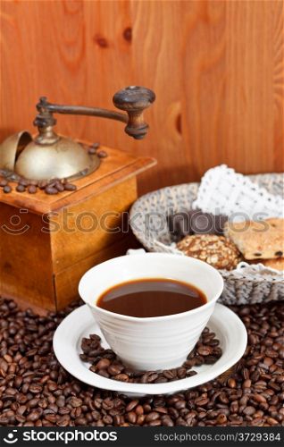 cup of coffee and roasted coffee beans with retro wooden manual mill, biscuit