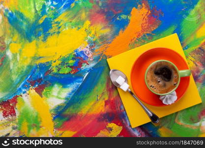 Cup of coffee and spoon with sugar at colorful abstract background texture. Coffee break time concept at abstract painting