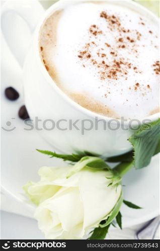 cup of coffee and white rose on white background