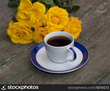 cup of coffee and yellow flowers on an old table