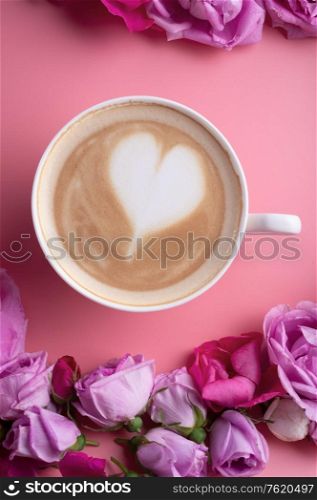 cup of coffee around may roses against pink background. romantic and beauty concept