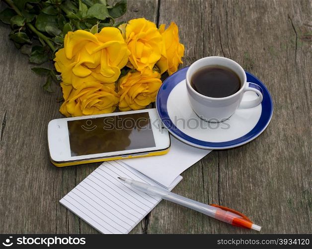 cup of coffee, bouquet of yellow roses, phone, the handle, the top view, on a wooden table, a still life, a subject beautiful flowers and drinks