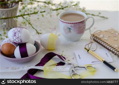 Cup of coffee , colorful fancy eggs and cherry blossom on white background. Easter concept