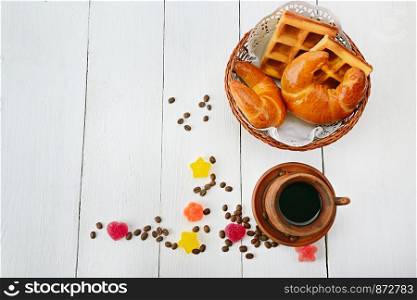 Cup of coffee, croissant, waffles and marmalade on wood white background. Free space for text. Flat lay, top view.