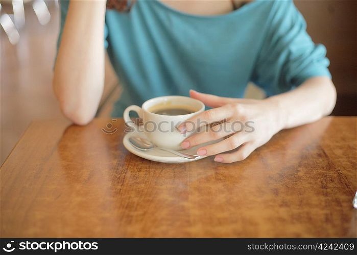 Cup of coffee in the women&acute;s hand on table