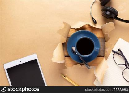 Cup of coffee in torn paper and clipboard. Coffee at cardboard background