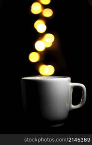 cup of coffee on black background, balls of light fall into coffee bokhes