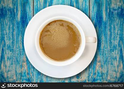 Cup of coffee on blue wooden surface, top view