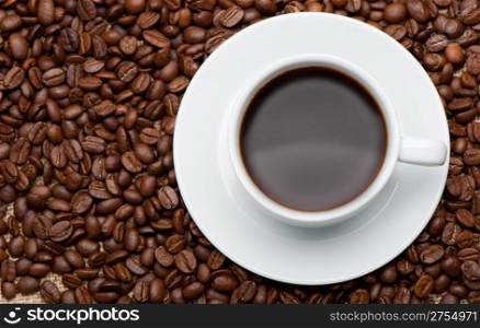 Cup of coffee on coffee grains. A hot drink