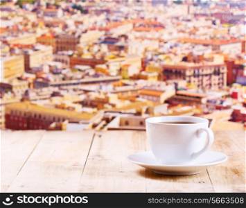 cup of coffee on wooden table over cityscape