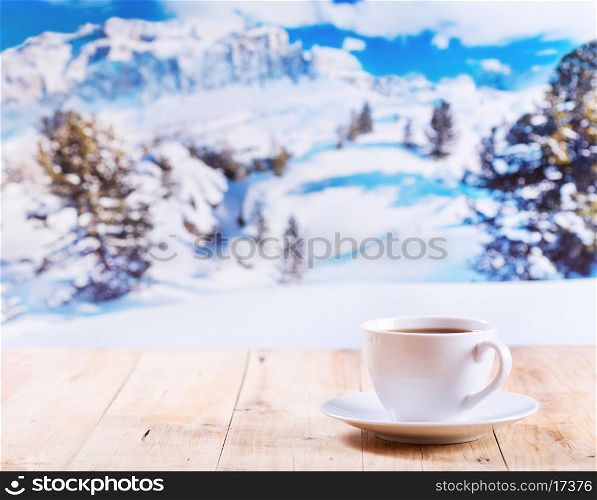 cup of coffee on wooden table over winter landscape