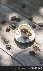 Cup of coffee on wooden table. Small miniature cup