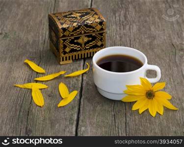 cup of coffee, petals, casket and yellow flower, still life, on a wooden table, a subject flowers and drinks