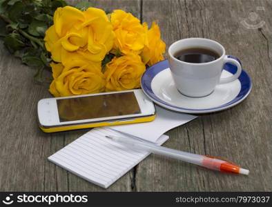cup of coffee, phone, bouquet of roses and notebook with the handle