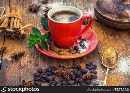 Cup of coffee. Red glass Cup with coffee on wooden background strewn with aromatic spices to drink