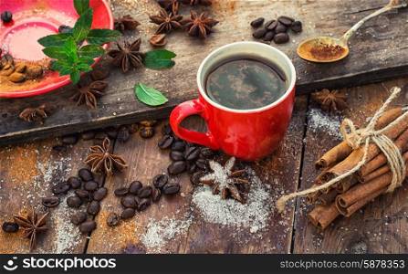 Cup of coffee. Red glass Cup with coffee on wooden background strewn with aromatic spices to drink