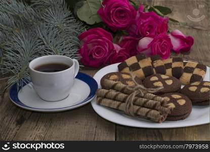 cup of coffee, roses and plate with different cookies on a table
