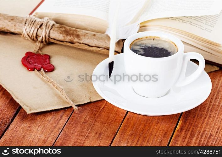 cup of coffee with a quill pen and parchment scroll of a book on wooden background