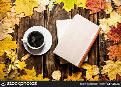 Cup of coffee with an old book and maple leaves. On wooden background.. Cup of coffee with an old book and maple leaves.