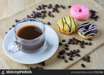 Cup of coffee with colorful doughnut in blur background  on wood table,selective focus.